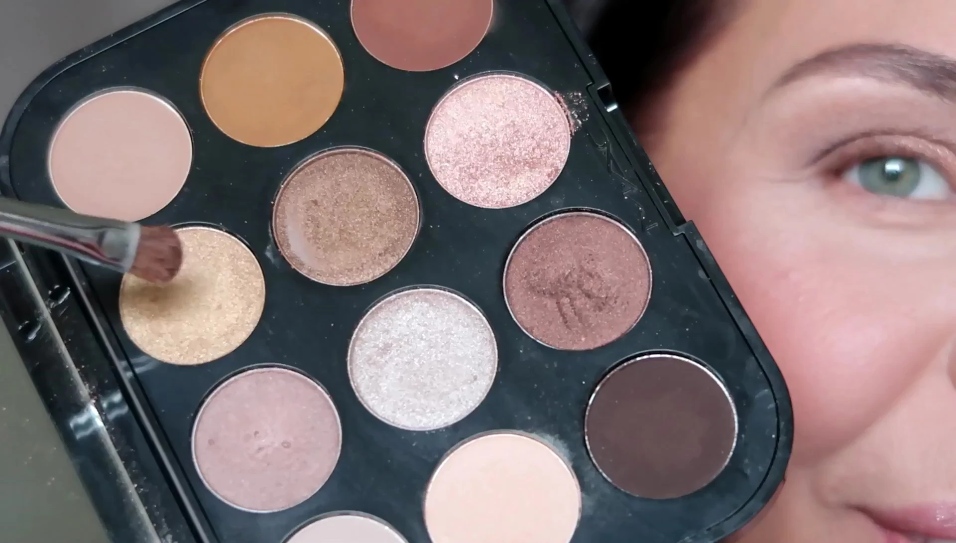 Applying gold eyeshadow to the center of the lid.