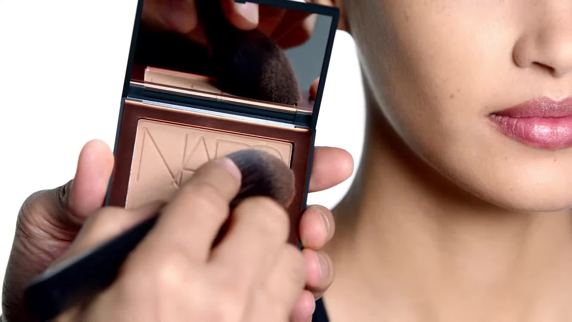 Demonstrating the application technique of the bronzer using circular motions.