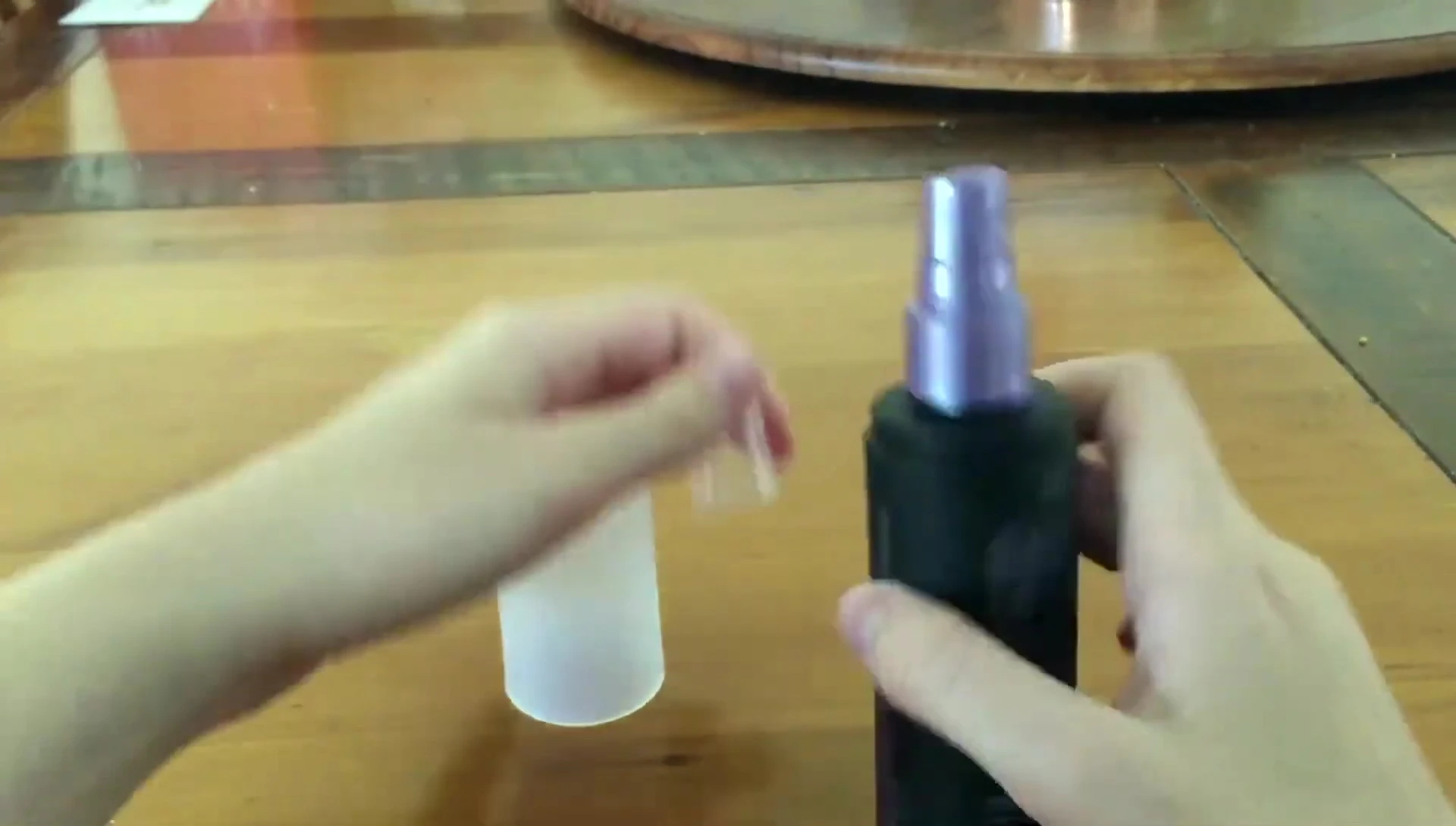 Close-up of the De-Slick setting spray bottle showing the dual-lid system.