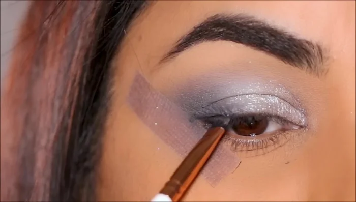 Create a small wing and liner using the black eyeshadow and an angled brush.