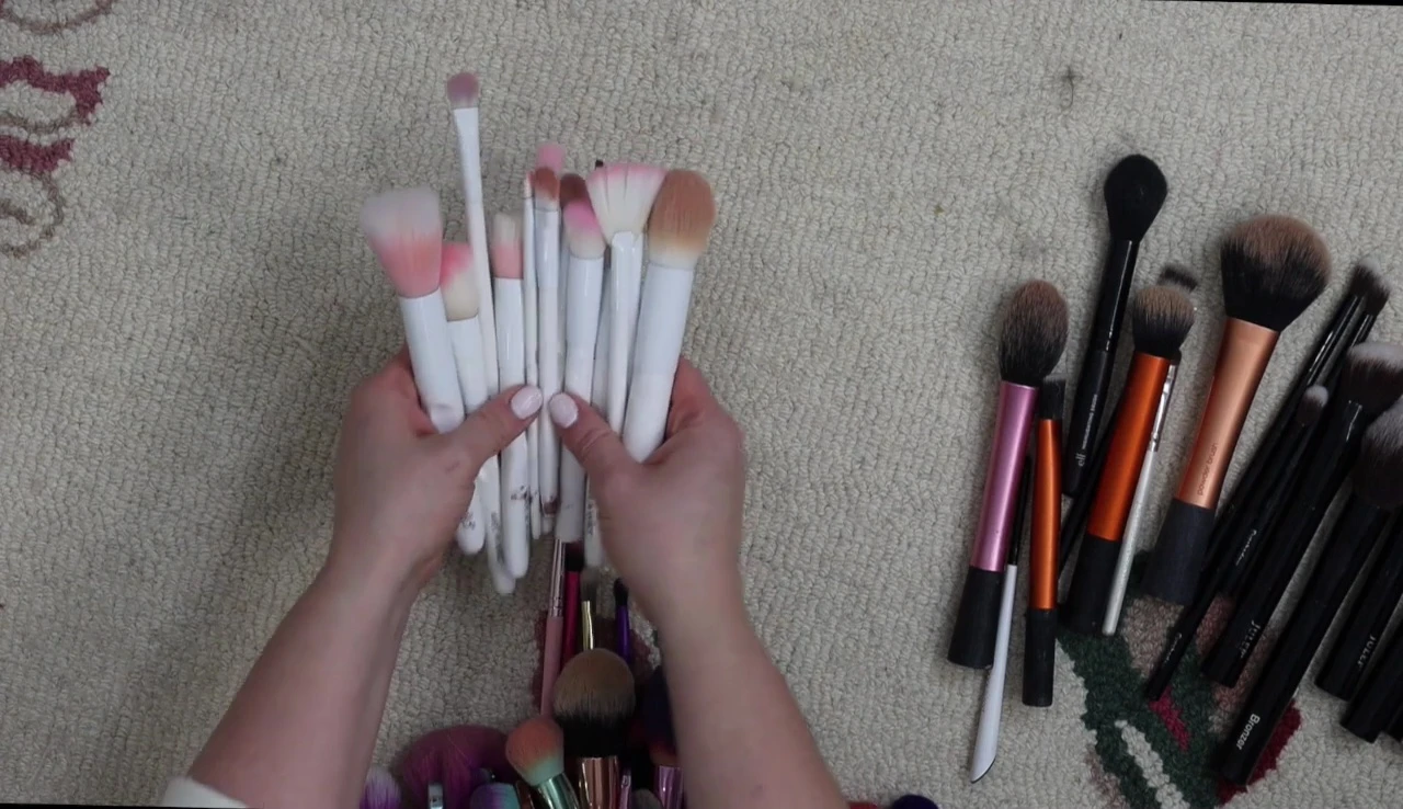 The speaker is holding up a pile of Wet n Wild brushes, preparing to donate them.