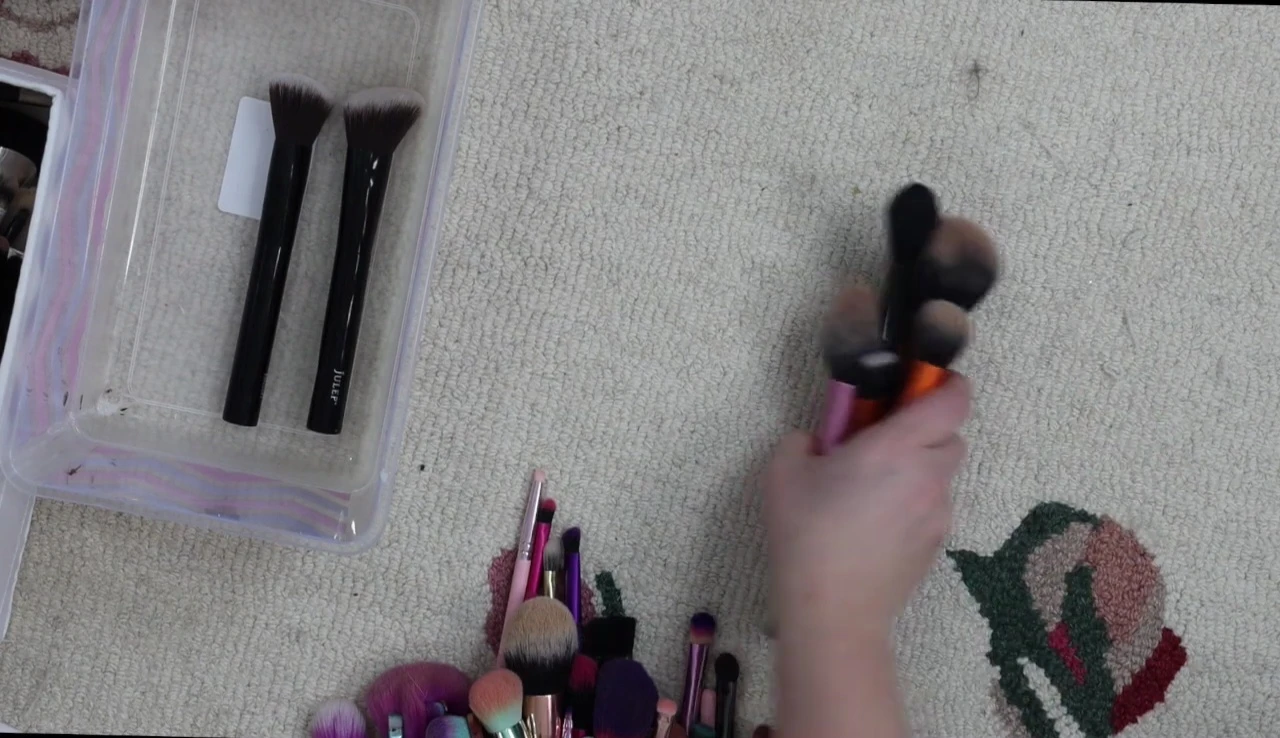 The speaker is showing a collection of what she terms 'good drugstore' brushes.
