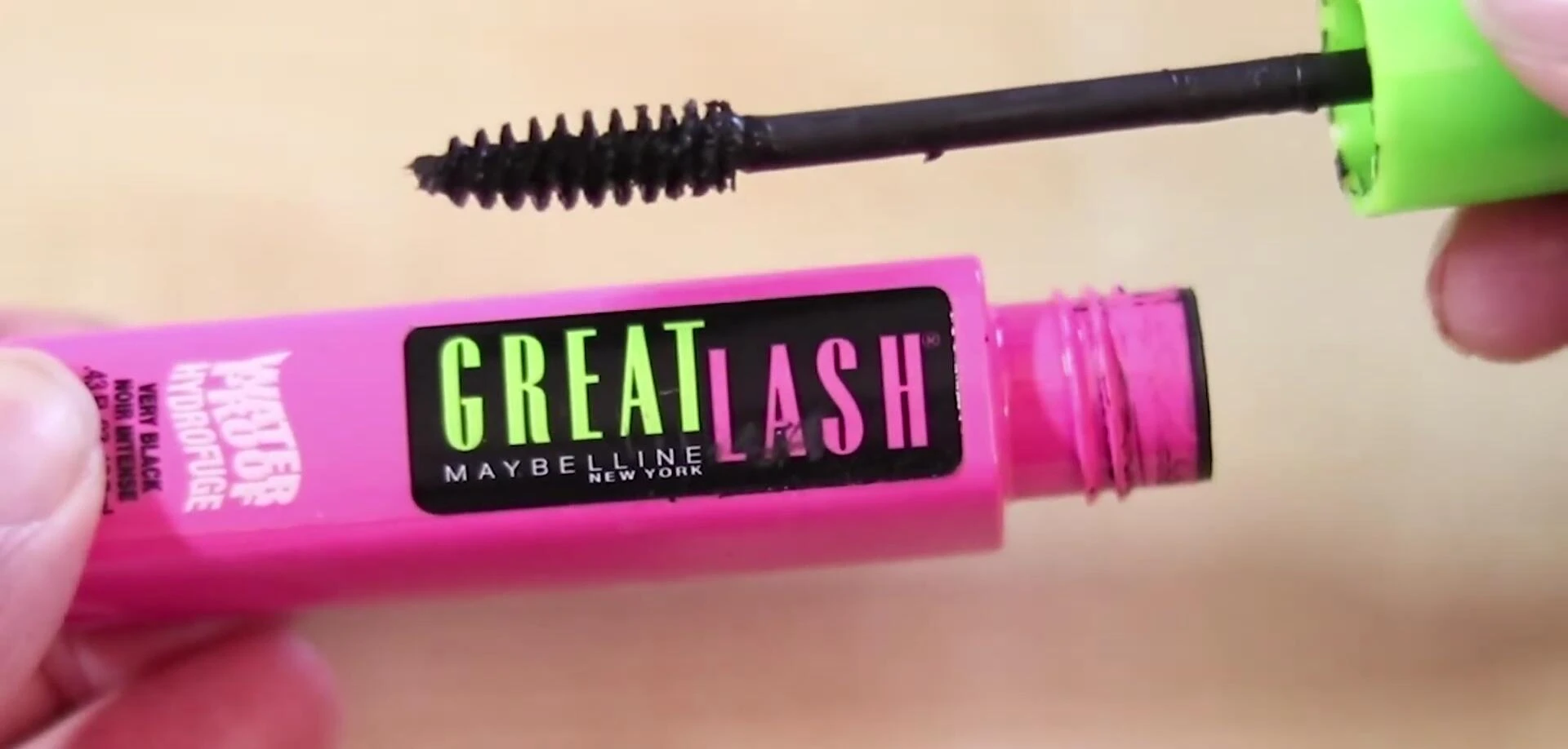 Shot of the mascara wand being removed from the green cap.