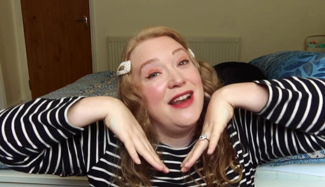 The reviewer giving a thumbs-up while wearing the lipstick