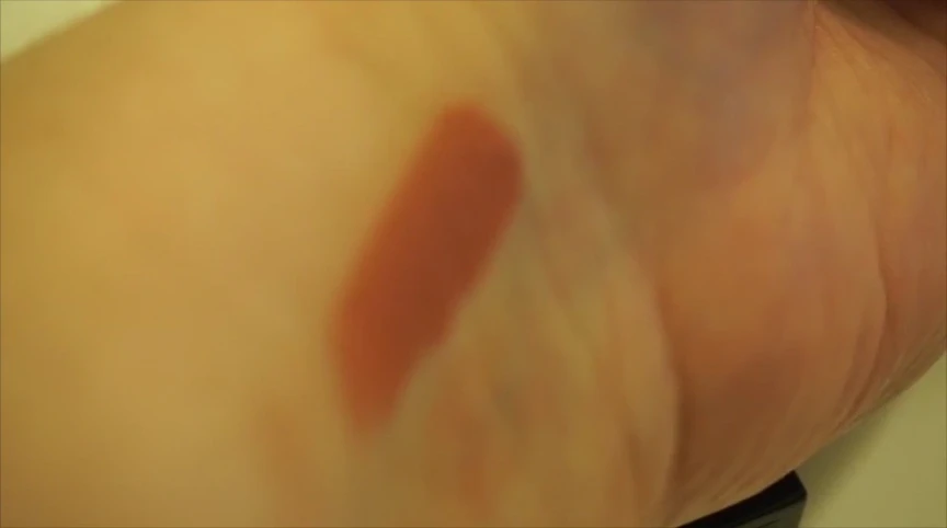 One swipe of Raquel lipstick on the model's lips showcasing the color payoff.