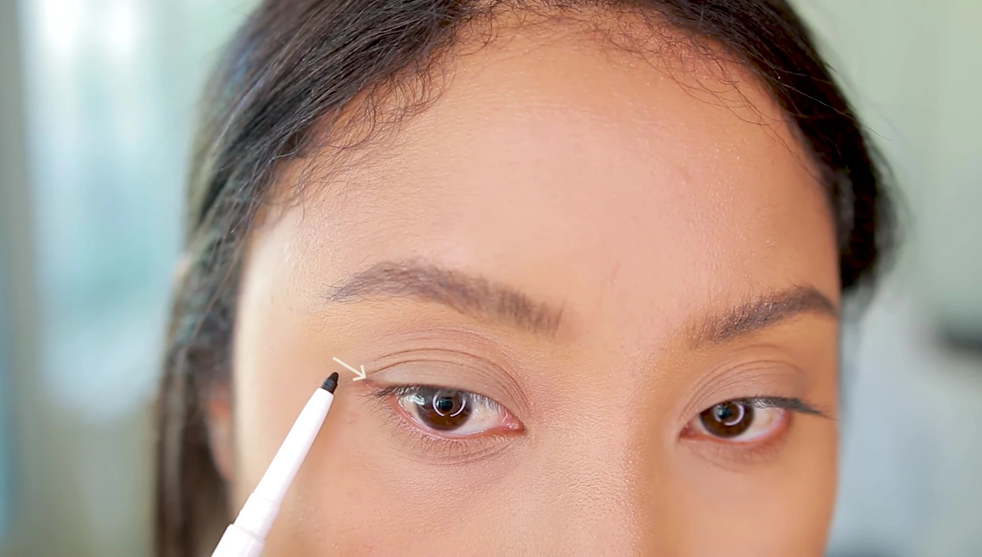 Demonstration of applying eyeliner from the outer corner.