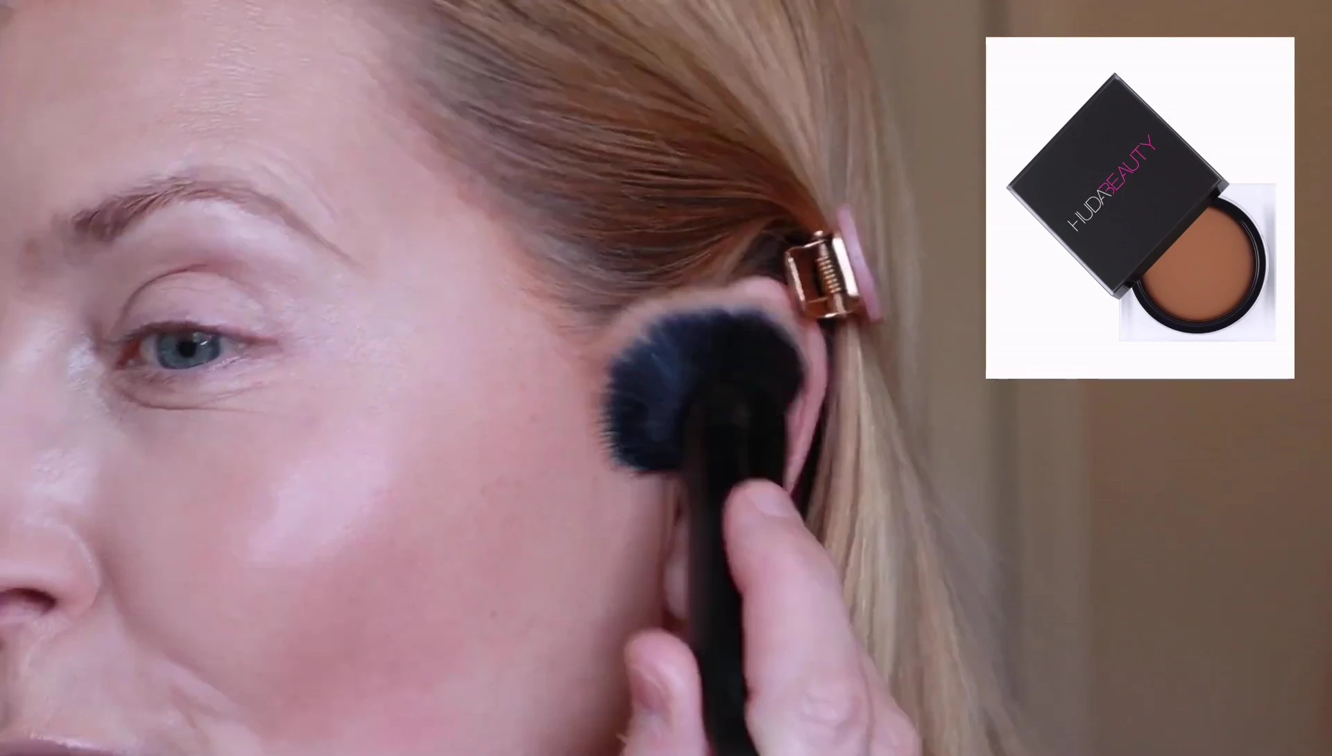 The model showcasing the Huda Beauty Tantour on one side of her face.