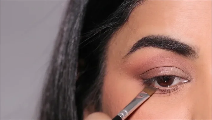 Apply the matte eyeshadow with shimmer specks to the lid using a flat shader brush. For extra intensity, add loose pigment eyeshadow with your fingertip.