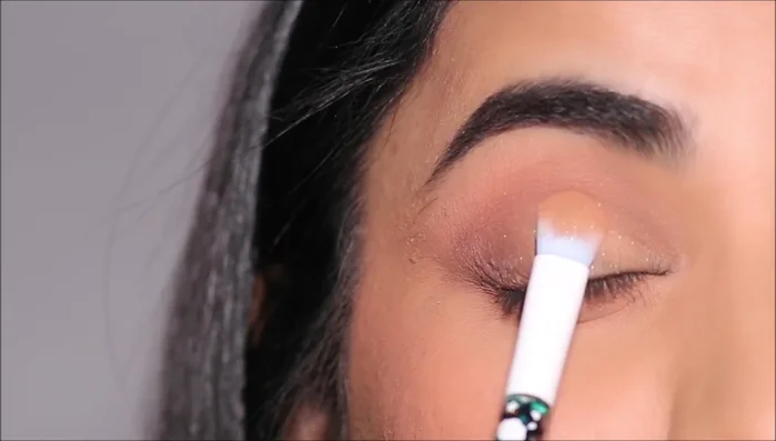 Apply the matte eyeshadow with shimmer specks to the lid using a flat shader brush. For extra intensity, add loose pigment eyeshadow with your fingertip.