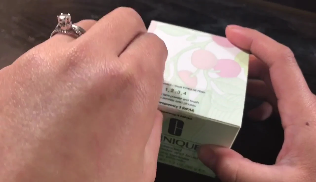 The speaker opens the Clinique powder compact to show the brush and powder.