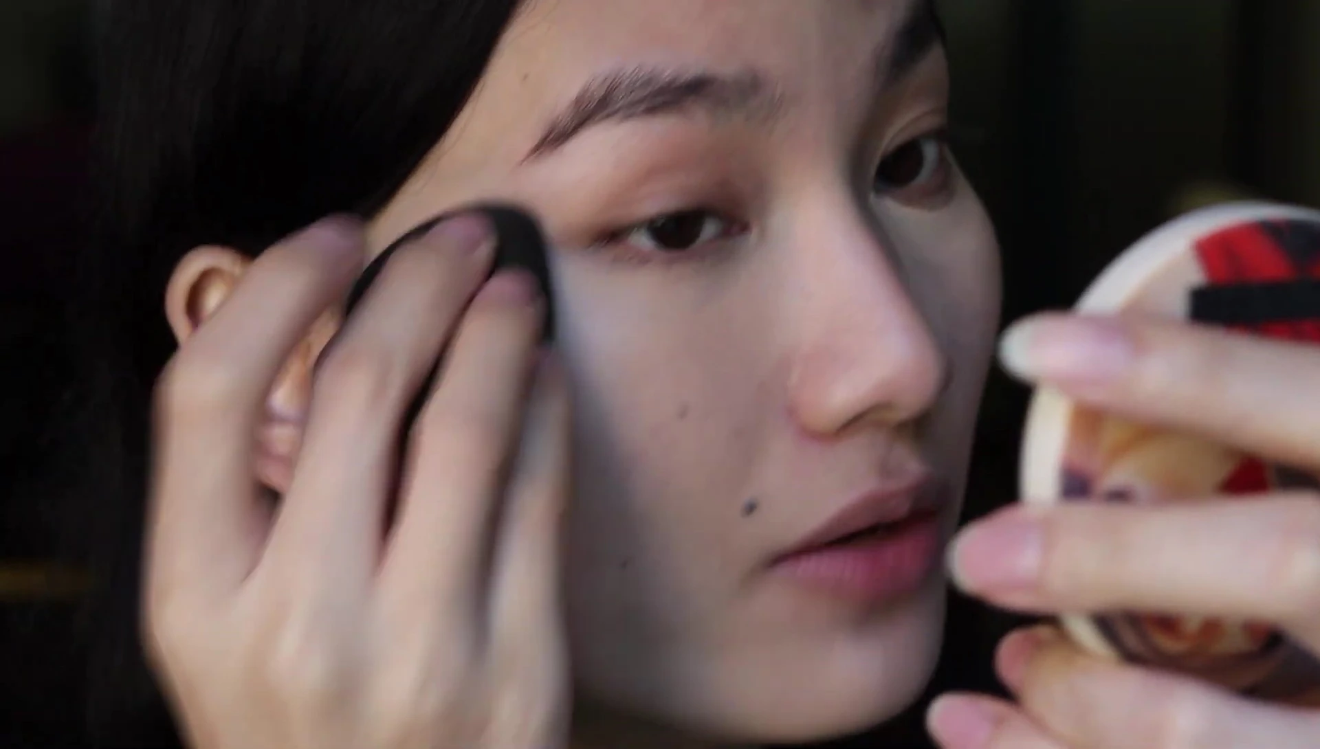 The reviewer demonstrating concealer application with the large sponge.