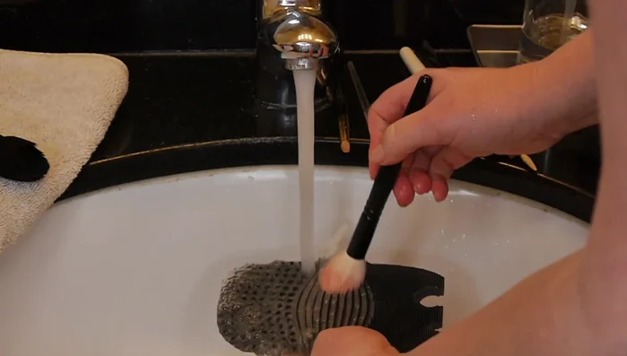 Rinse the brushes: Rinse the brushes under lukewarm water, gently scrubbing them back and forth on the silicone mat to remove the makeup and cleanser. Hold the mat firmly in your hand for better control.