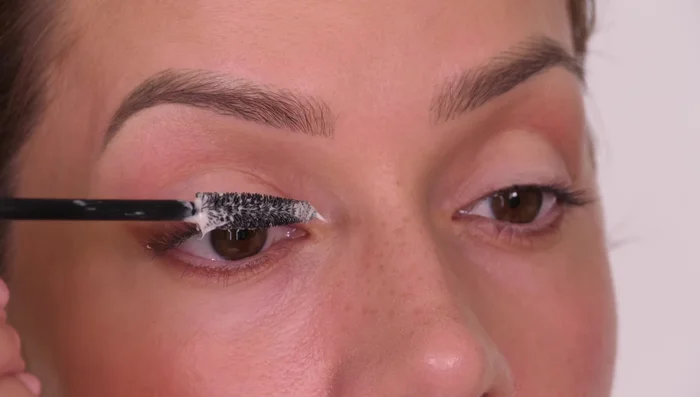 Apply mascara, looking down into a mirror to avoid smudging on the lid. Curl lashes with a curler, focusing on the outer third for a lifted effect.